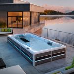 endless pools swim spa e series sunken into concrete patio behind a modern style dimly lit home on a lake